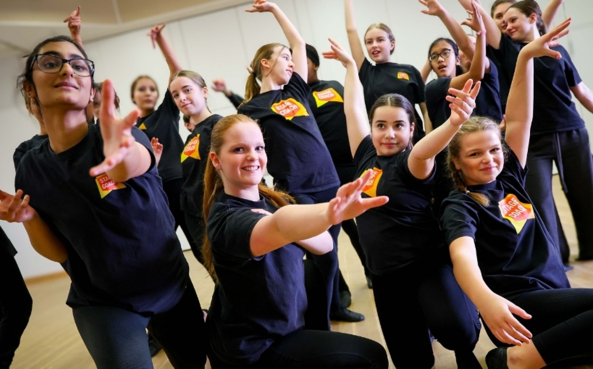 Stagecoach students performing an expressive group dance routine with their arms extended