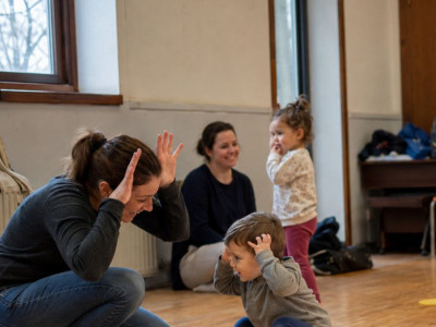 Parents and toddlers taking part in a playful movement activity together in a community hall class